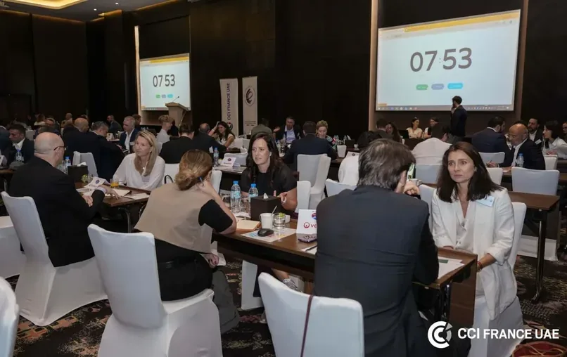 Session de matchmaking B2B au Working Together Forum de la CCI France UAE à Dubaï, participants assis à des tables avec des comptes à rebours projetés.
