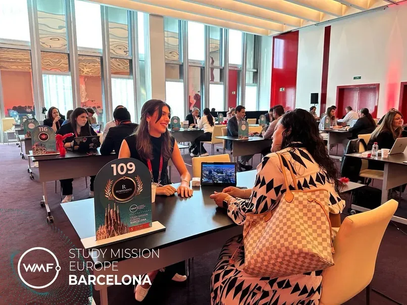 Rendez-vous B2B dans une salle lumineuse au WMF Study Mission Europe à Barcelone, participants à des tables numérotées (table 109 visible), laptops ouverts.