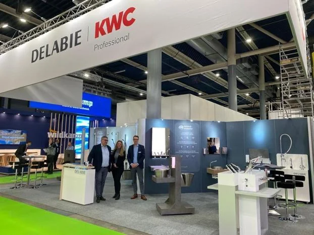 Le stand Delabie et KWC Professional sur un salon, avec des membres de l'équipe devant les produits