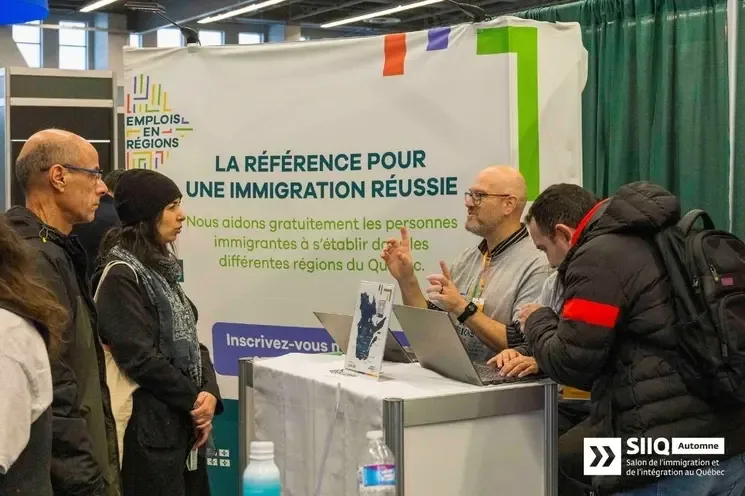 A MIFI team member speaking with candidates at an Emplois en régions booth during a Quebec immigration event