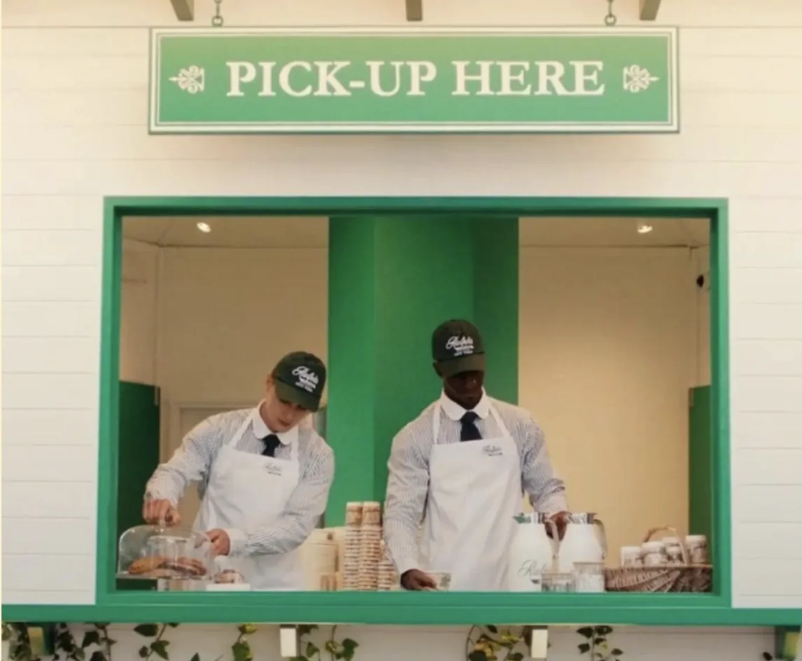 Équipe en casquettes et tabliers Ralph's Coffee au comptoir de retrait d'une activation estivale de Ralph Lauren